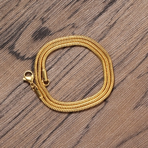 Detail of 2mm gold-plated snake chain necklace with lobster clasp on wood background