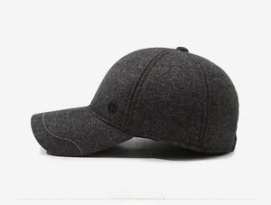 Detailed side view of dark grey tweed baseball cap with earmuffs and round decorative badge