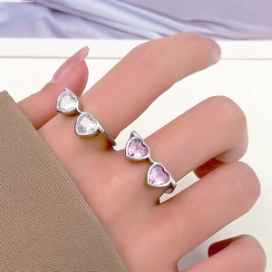Detailed close-up of heart-cut zircon rings in clear white and sweet pink on hands
