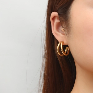 Minimalist double hoop gold earrings made of titanium steel worn by a female model