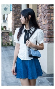 Detail shot of a blue floral shoulder bag styled with a white shirt and denim skirt