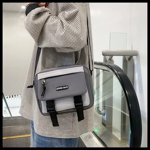 On-model shot of a gray and white messenger bag with buckle and adjustable strap