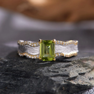 S925 sterling silver ring with rectangular green peridot on a natural rock surface