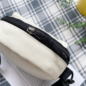 Close-up of off-white canvas crossbody bag showing coarse fabric texture and black zipper