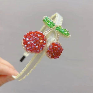 Close-up of handmade beaded cherry headband with red crystals and green leaves details