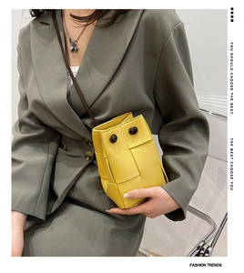 Detail of yellow hand-woven bucket bag featuring a knot handle and elegant PU leather texture