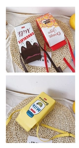 Flat lay detail of milk box shaped crossbody bags on a woven mat with citrus accents