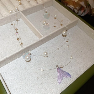 Macro shot of iridescent mermaid tail pendant and white pearls in jewelry box