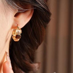 Macro view of gold vintage earrings with tiered amber and brown faceted crystals on a model