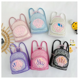 Flat lay of colorful sequin shell backpacks for girls featuring pearl bead handles