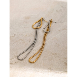 Macro detail of long snake chain earrings in gold and silver finish on stone texture