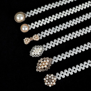 Detail of double-strand pearl waist chains with sparkling rhinestone buckles on black background