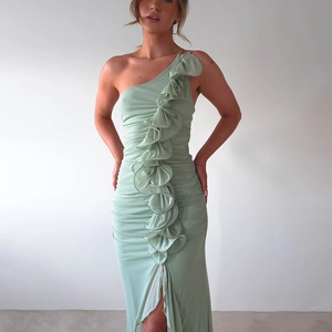 Détail d'une robe asymétrique vert clair avec volants décoratifs et fente haute