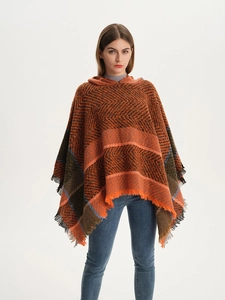 Detailed texture of herringbone knit pattern and tassel fringe on hooded poncho cape
