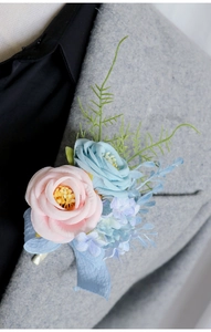 Close-up of a pink and blue boutonniere with ribbon on a grey suit lapel for weddings