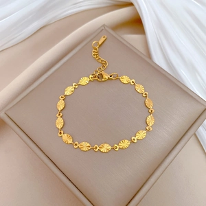 Detail of a gold titanium steel bracelet with oval textured links on a silk background