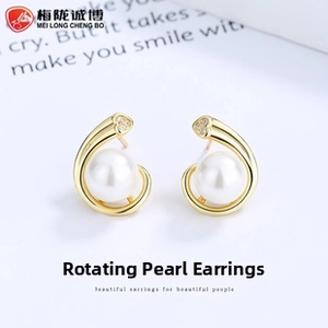 Macro detail of gold C-shaped earrings with round pearl and sparkling heart stud