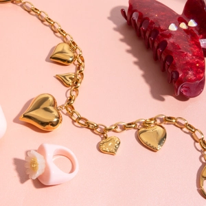 Close-up of golden 18K heart pendants on chunky chain with luxury textured background