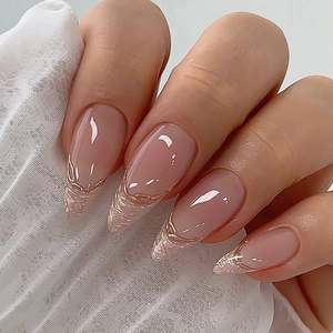 Long almond press-on nails with nude pink base and gold glitter french tips