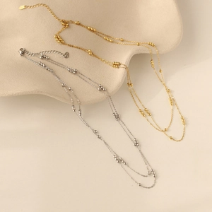 Detail of gold and silver double-layer beaded necklaces on a minimalist display
