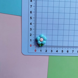 Close-up of a blue and pink resin frangipani flower accessory on a measuring mat
