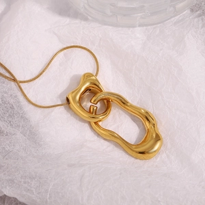 Detail of interlocking irregular gold rings pendant on a layered paper background