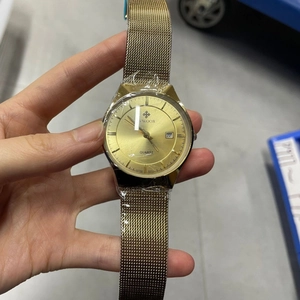 Close-up of golden quartz watch with metal mesh strap and date calendar feature