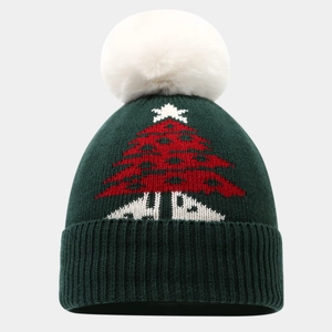 Detail einer grünen Strickmütze mit Bommel und festlichem Weihnachtsbaum-Muster