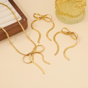 Flat lay of gold bow necklace and earrings set with elegant snake chain texture