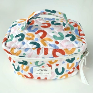 Close-up of quilted cosmetic bag featuring abstract colorful patterns and ribbon zipper pull