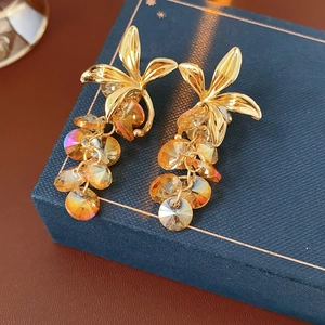 Detailed macro of vintage gold bow earrings with amber crystal beads in a jewelry box