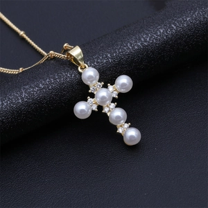 Detailed shot of a gold-plated cross pendant necklace with pearls and sparkling crystals