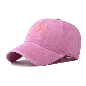 Dettaglio cappellino in cotone lavato rosa con ricamo a fiocco arancione e fibbia metallica