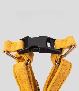 Detailed view of yellow suede dog harness with secure black buckle and metal D-rings