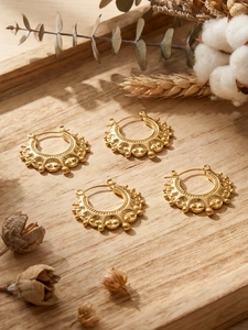 Macro detail of U-shaped gold crown hoop earrings with vintage bohemian relief patterns