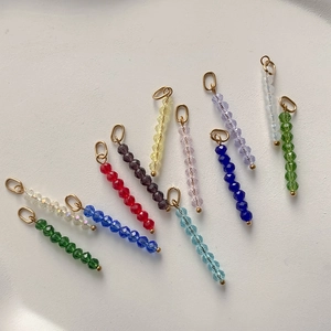Macro-opname van elf kleurrijke gefacetteerde kralenhangers met goudkleurige ringen