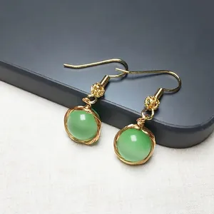 Vue détaillée des boucles d'oreilles en fil d'or 14K et pierre oeil de chat verte