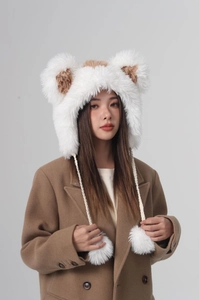 Detailed view of white faux fur winter bucket hat with brown ears and warm fluffy pom poms