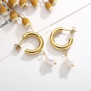 Détail de boucles d'oreilles créoles en forme de C plaqué or 18K avec perles blanches