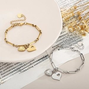 Detail of gold and silver heart pendants on chunky chain bracelets with a luxury finish