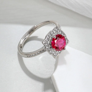 Close-up of a silver ring featuring a pink corundum main stone with clear side crystals