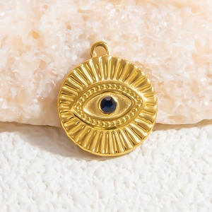 Macro detail of gold evil eye pendant featuring a deep blue gemstone on stone texture