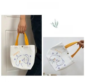 Detail of canvas bag with yellow handle, happy dog print and metal snap button closure