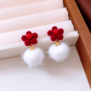 Makro-Detail roter beflockter Blumenohrringe mit weißem Plüsch-Pompon und Goldakzenten