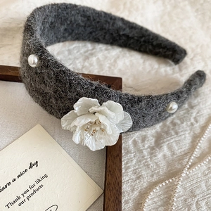 Detailed close-up of a charcoal grey wool headband featuring white fabric flowers and pearls