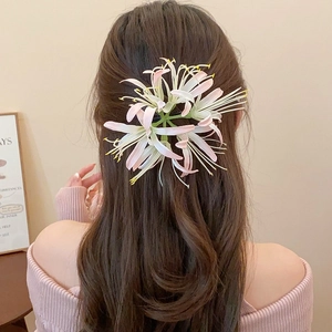 Detail of pink acrylic flower hair clip worn on long wavy hair from back view