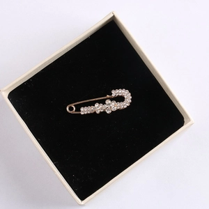 Macro view of rose gold safety pin brooch with crystals in beige velvet jewelry box