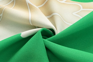 Close-up of printed swimwear fabric with green and beige floral patterns and crepe texture