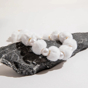 Gros plan de pompons blancs et perles brillantes sur un collier sur pierre sombre