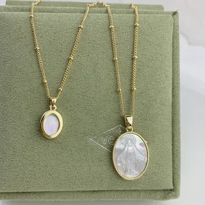 Detailed macro of golden chains with Mother Mary relief on white shell pendants